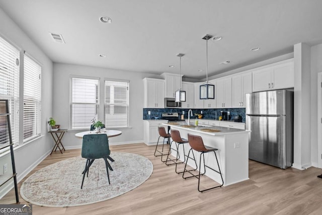kitchen featuring visible vents, white cabinetry, a breakfast bar, and stainless steel appliances