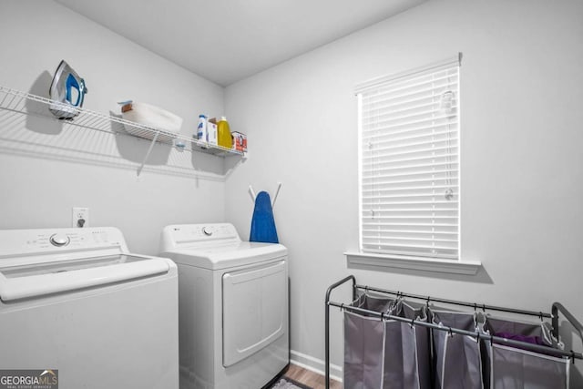 laundry area with laundry area, washing machine and dryer, and wood finished floors