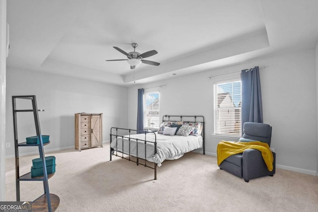 bedroom with baseboards, carpet flooring, a raised ceiling, and a ceiling fan