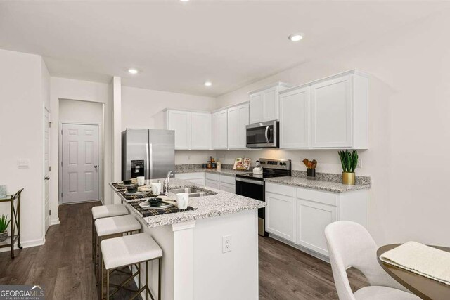 309 Elgin Dr, Lawrenceville, GA 30045 - kitchen with appliances with stainless steel finishes, a kitchen bar, a sink, white cabinetry, and dark wood-type flooring