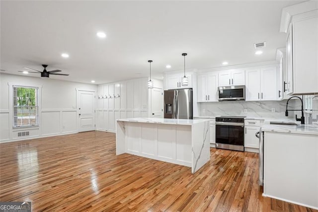 kitchen featuring light wood finished floors, a sink, white cabinets, and stainless steel appliances
