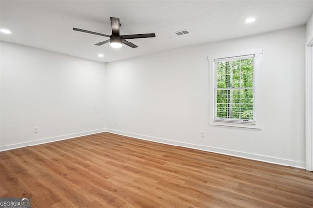 empty room with baseboards, recessed lighting, wood finished floors, and visible vents