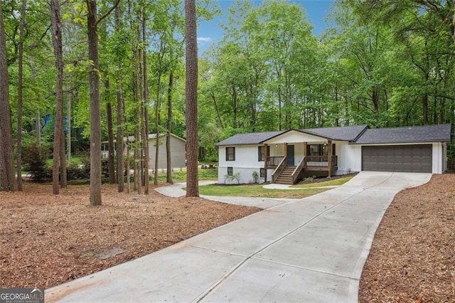 single story home featuring driveway, an attached garage, and covered porch