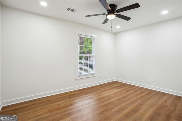 empty room with wood finished floors, recessed lighting, visible vents, and baseboards