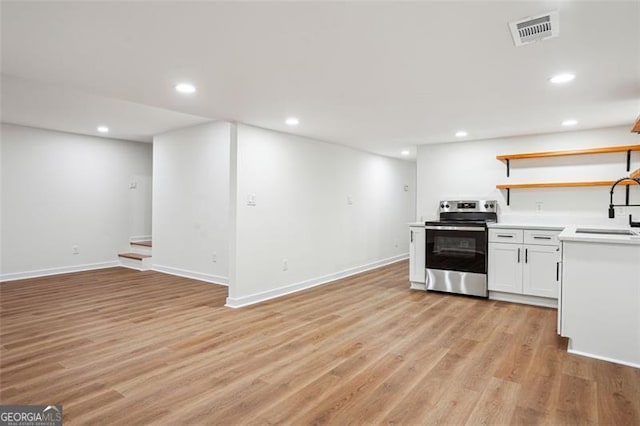 kitchen with light wood finished floors, a sink, open shelves, visible vents, and electric range