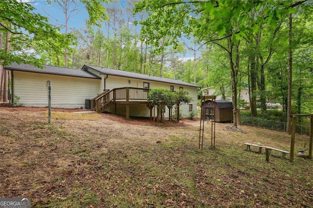 back of property featuring an outdoor structure, a storage unit, a deck, fence, and stairway