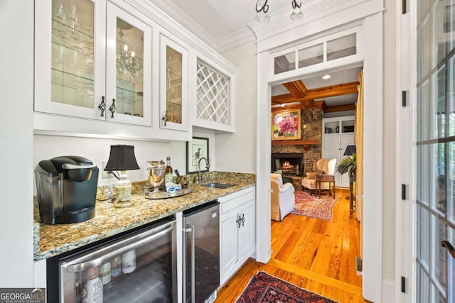 bar featuring crown molding, wine cooler, wet bar, and light wood-type flooring