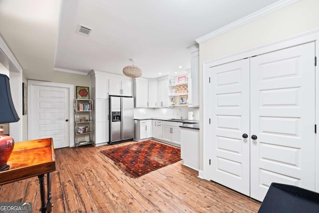kitchen featuring open shelves, stainless steel fridge, white cabinets, a sink, and visible vents