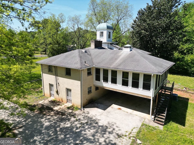 11433 Panhandle Rd, Hampton, GA 30228 - back of house with a chimney, stairs, driveway, roof with shingles, and a lawn