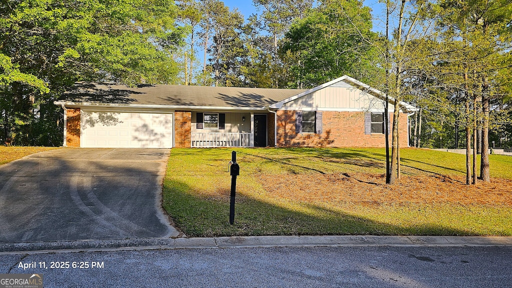 ranch-style home with a garage, brick siding, driveway, and a front yard