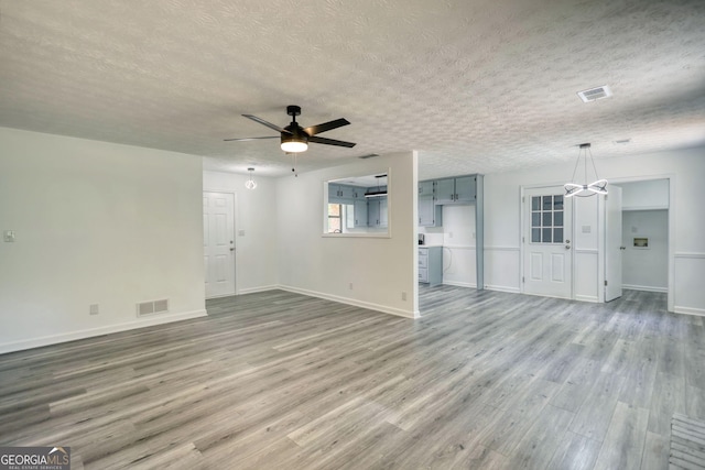 2931 Randolph Ct NE, Conyers, GA 30012 - unfurnished living room with visible vents, a textured ceiling, ceiling fan with notable chandelier, and wood finished floors