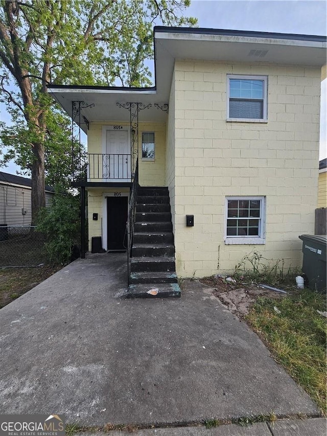 view of front of home with stairway and concrete block siding