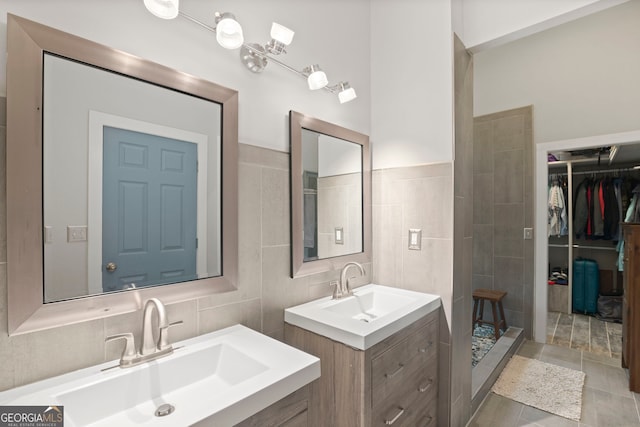 43 Cowan Ct, Mansfield, GA 30055 - bathroom with two vanities, a spacious closet, a tile shower, tile walls, and tile patterned flooring