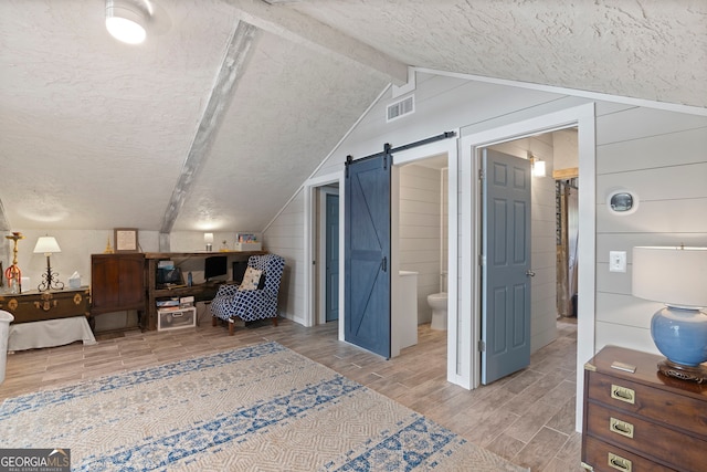 43 Cowan Ct, Mansfield, GA 30055 - bedroom featuring wood tiled floors, a textured ceiling, a barn door, and ensuite bathroom