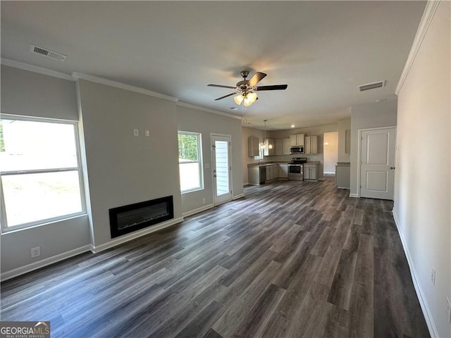 unfurnished living room featuring a ceiling fan, visible vents, baseboards, ornamental molding, and dark wood-type flooring