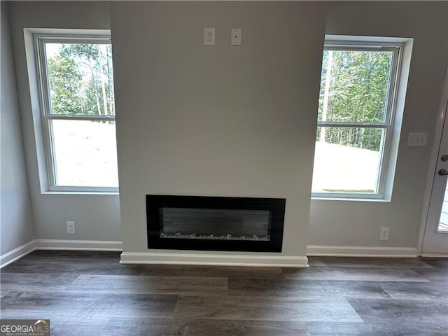 interior space featuring baseboards, a glass covered fireplace, and wood finished floors