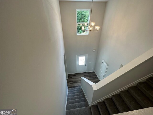 staircase with baseboards, a wealth of natural light, a high ceiling, and a notable chandelier