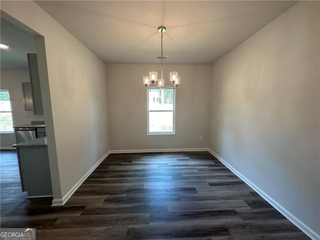 unfurnished dining area with dark wood-type flooring, baseboards, a notable chandelier, and visible vents