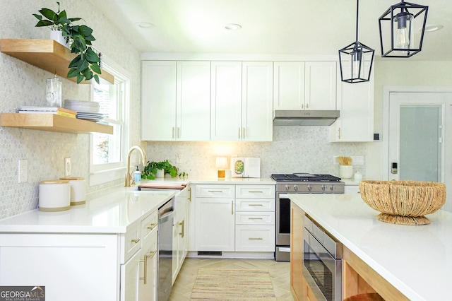 kitchen featuring under cabinet range hood, white cabinetry, appliances with stainless steel finishes, and a sink