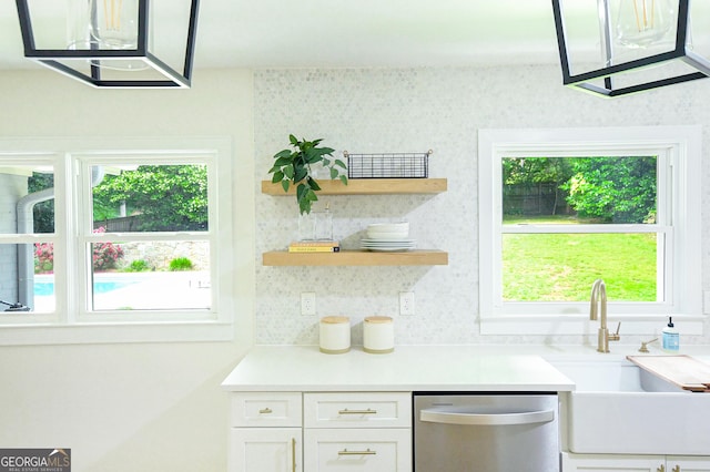 kitchen featuring stainless steel dishwasher, white cabinets, a healthy amount of sunlight, and a sink