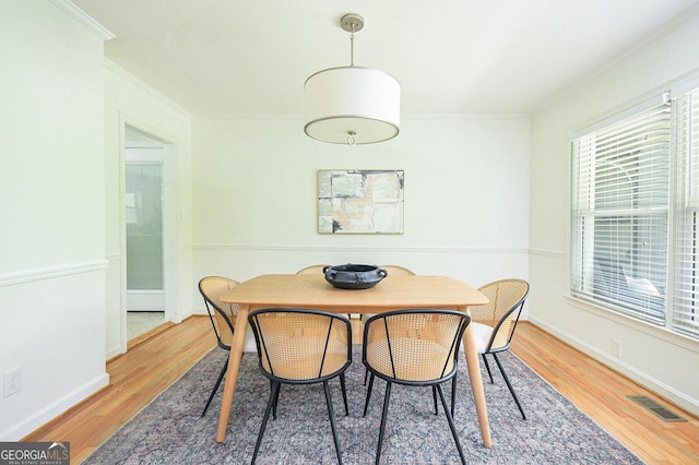 dining area with baseboards, visible vents, ornamental molding, and wood finished floors