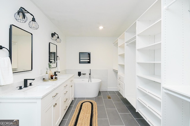 bathroom featuring a sink, a freestanding tub, tile patterned flooring, and double vanity