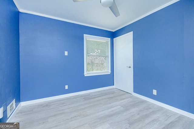 spare room with ceiling fan, baseboards, wood finished floors, visible vents, and ornamental molding