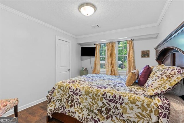 bedroom featuring visible vents, baseboards, ornamental molding, a textured ceiling, and wood finished floors