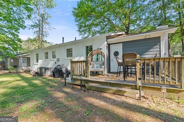 back of house featuring a lawn and a wooden deck