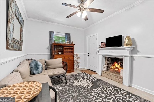 tiled living room featuring crown molding, a ceiling fan, baseboards, and a warm lit fireplace