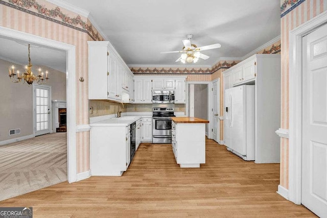 kitchen featuring butcher block countertops, stainless steel appliances, ceiling fan with notable chandelier, a sink, and visible vents