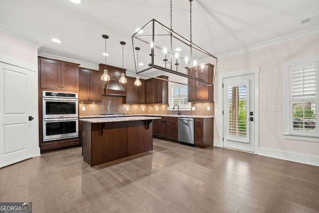 kitchen with ornamental molding, appliances with stainless steel finishes, a healthy amount of sunlight, and range hood
