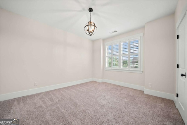 carpeted spare room featuring baseboards, a chandelier, and visible vents