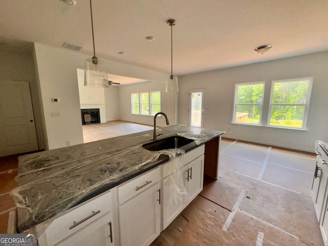 7252 Eton Ln, Locust Grove, GA 30248 - kitchen featuring visible vents, a fireplace, open floor plan, white cabinetry, and a sink
