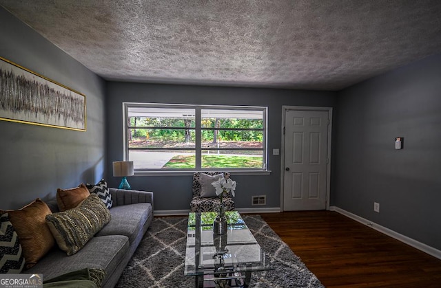 living area featuring baseboards, visible vents, wood finished floors, and a textured ceiling