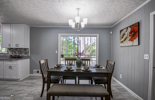dining space featuring a textured ceiling, crown molding, visible vents, baseboards, and an inviting chandelier