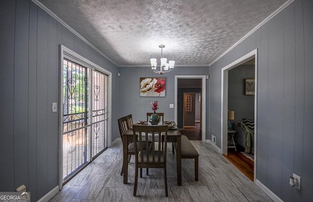 dining room with wood finished floors, baseboards, a notable chandelier, a textured ceiling, and crown molding