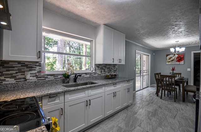 kitchen with decorative backsplash, a chandelier, electric range, a sink, and a textured ceiling