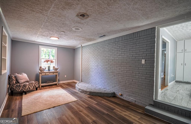 living area with ornamental molding, baseboards, wood finished floors, and brick wall