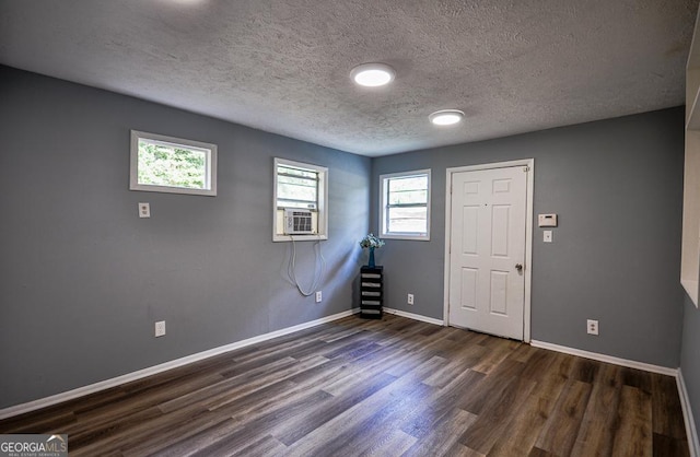 interior space with a textured ceiling, dark wood-style flooring, and baseboards