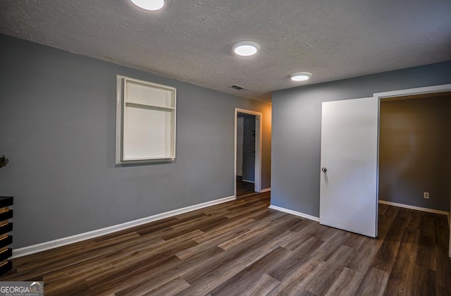 unfurnished bedroom with baseboards, visible vents, a textured ceiling, and dark wood-type flooring