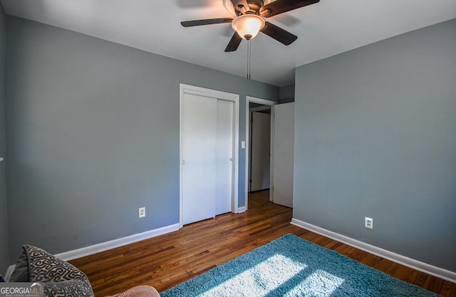 unfurnished bedroom featuring wood finished floors, ceiling fan, a closet, and baseboards