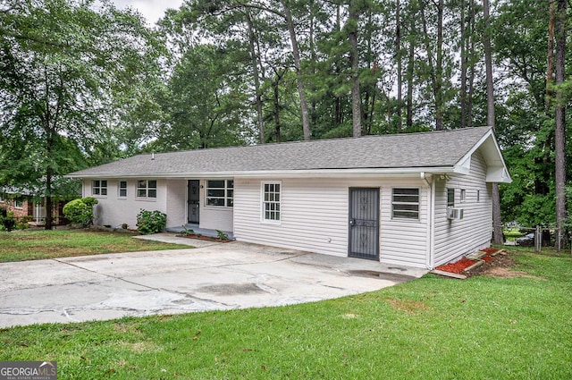 ranch-style home featuring roof with shingles, a front yard, and a patio area