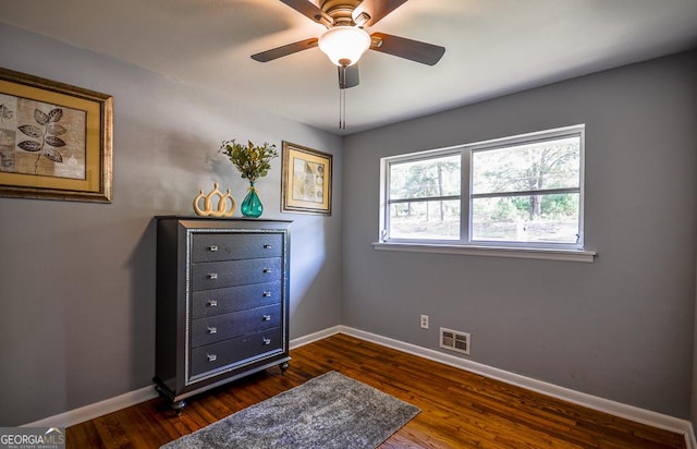 bedroom featuring dark wood-type flooring, a ceiling fan, visible vents, and baseboards