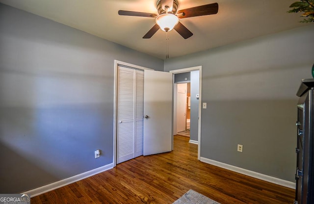 unfurnished bedroom with a closet, ceiling fan, wood finished floors, and baseboards