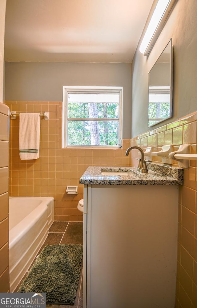 bathroom featuring tile walls, toilet, tile patterned flooring, and a bathing tub
