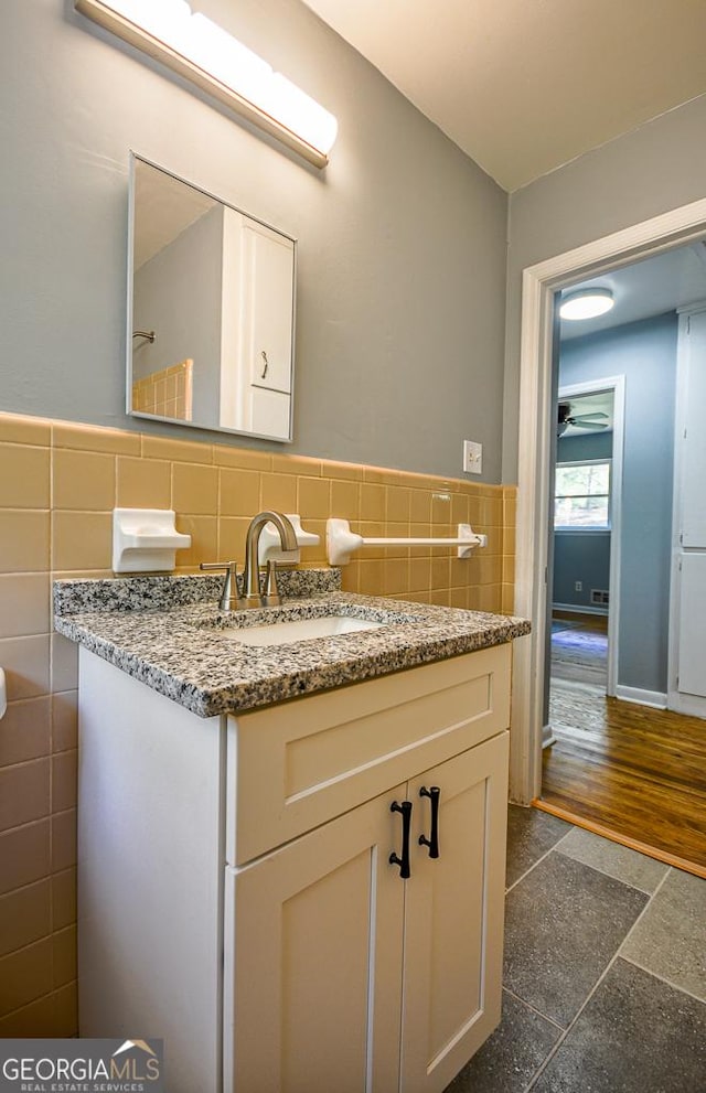 half bathroom with tile walls, a wainscoted wall, and vanity