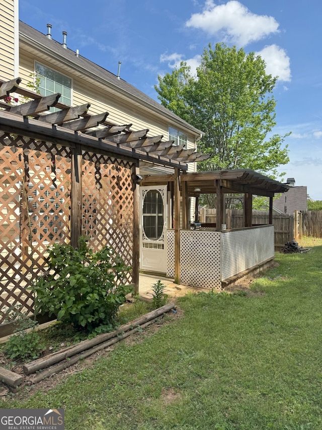 rear view of house featuring a pergola, fence, and a lawn