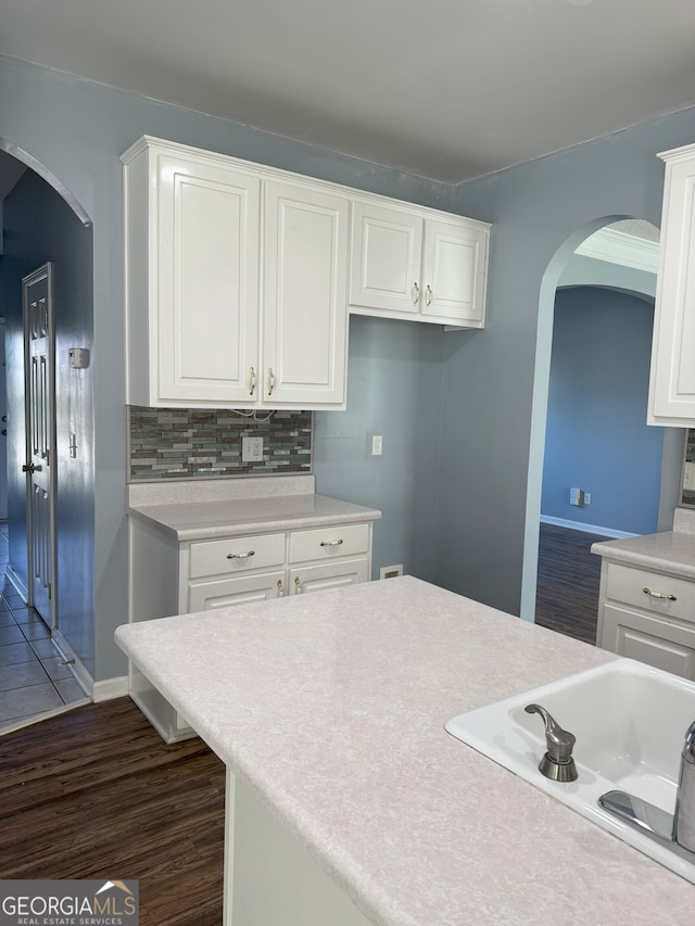 kitchen with white cabinets, light countertops, and arched walkways