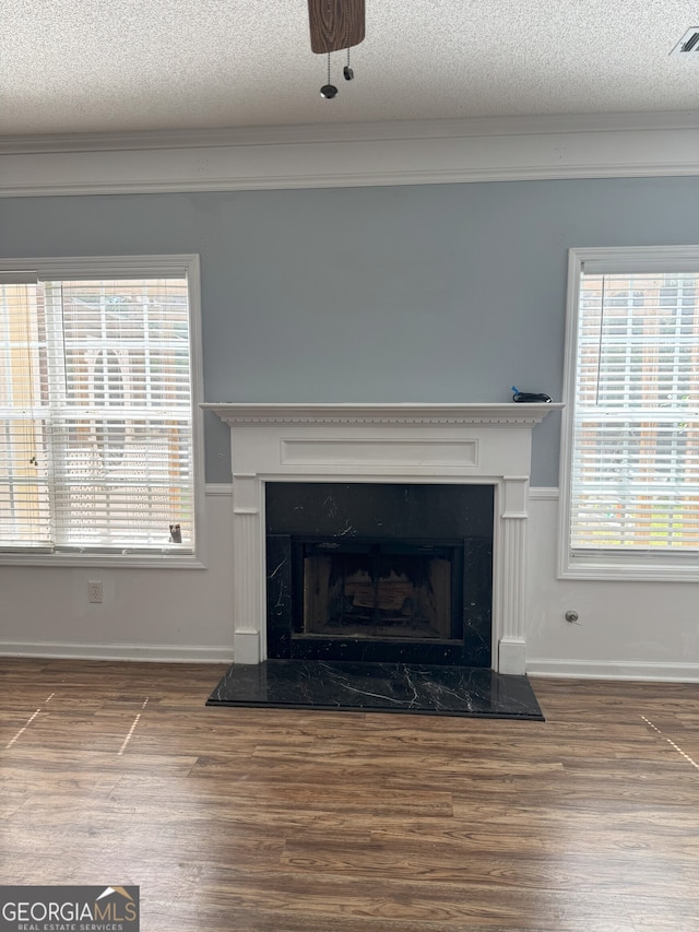 interior details featuring a fireplace, a textured ceiling, baseboards, and wood finished floors